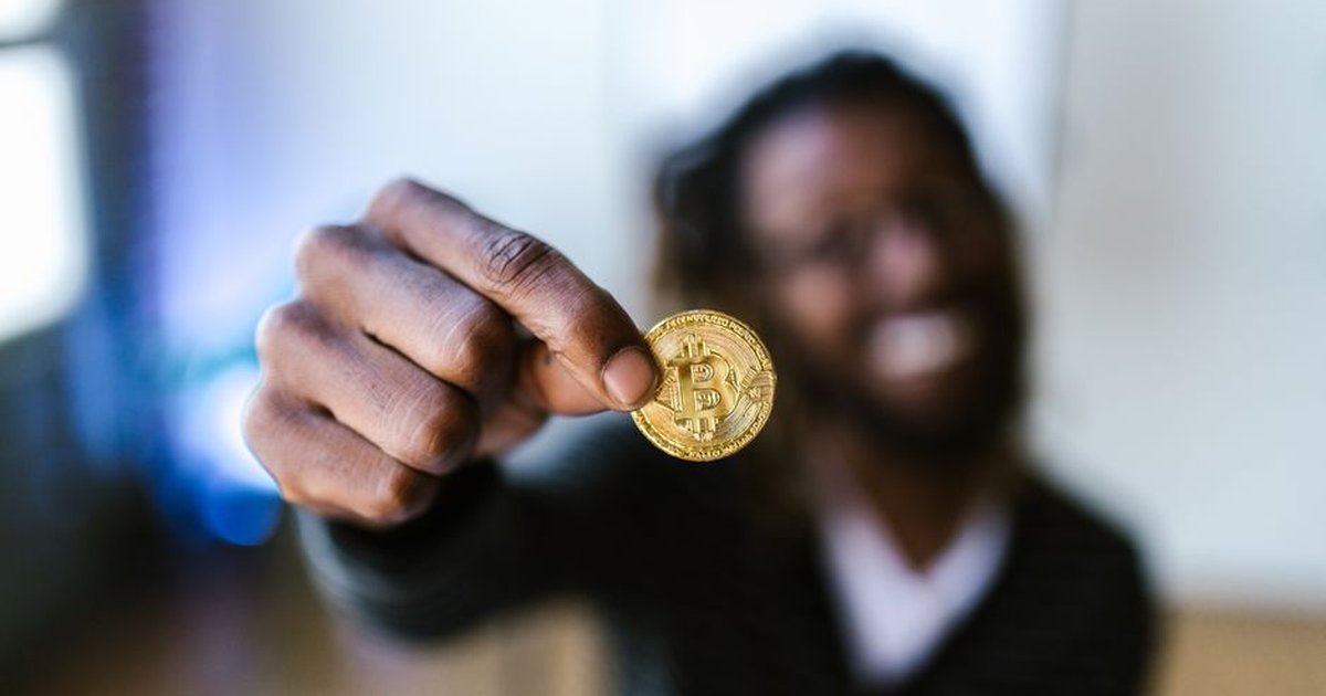 A person holding a Bitcoin coin, representing cryptocurrency and digital finance concepts.