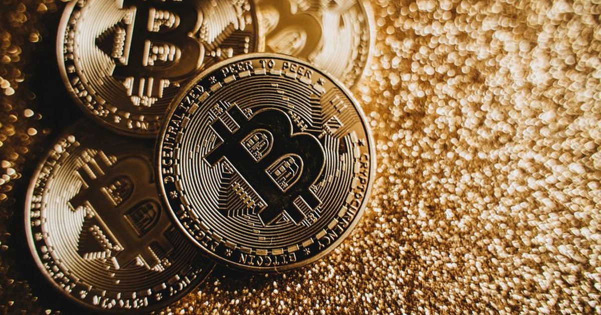 Close-up of Bitcoin cryptocurrency coins on a sparkling gold glitter background, symbolizing digital finance.