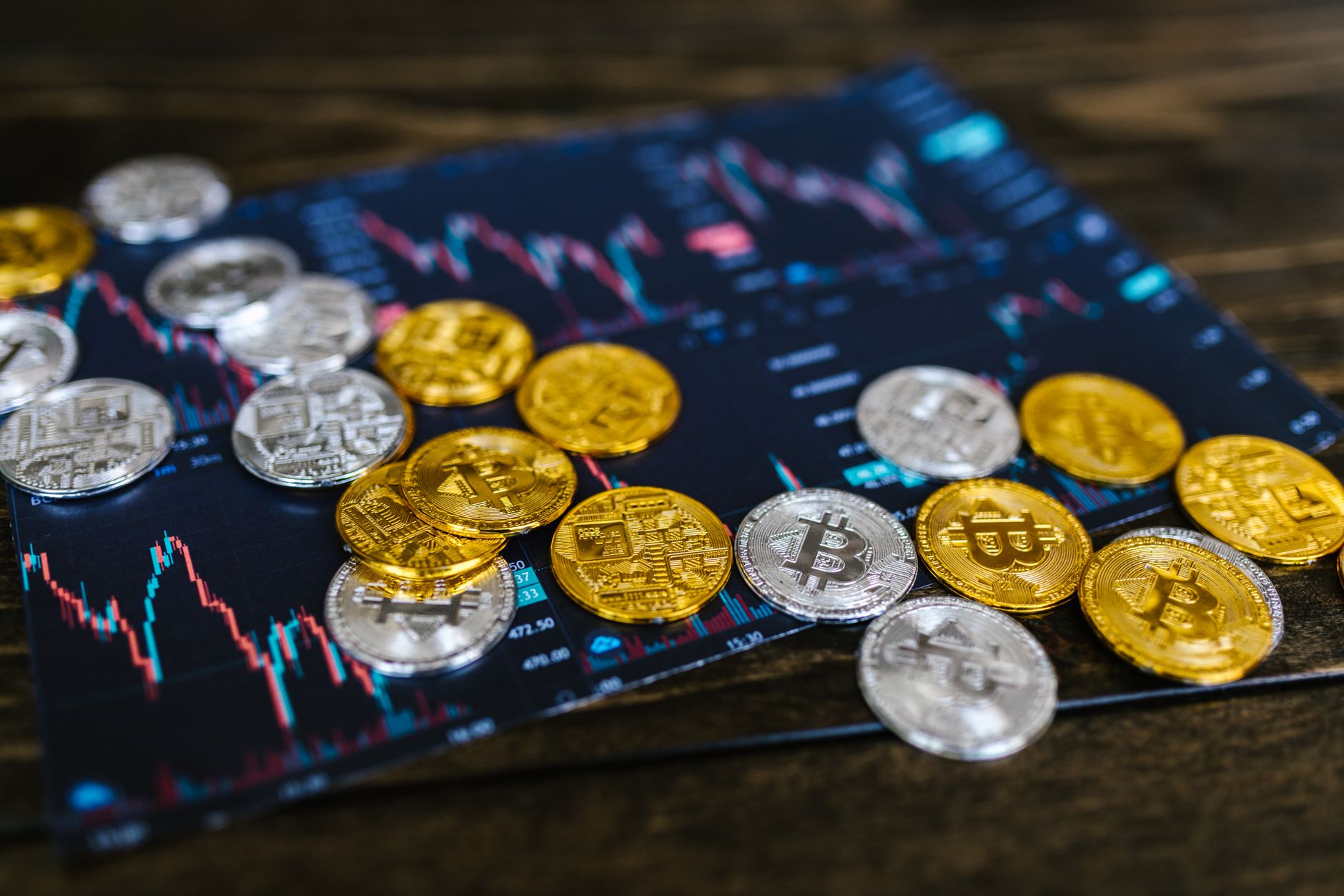Close-up of gold and silver cryptocurrency coins on a digital trading chart.