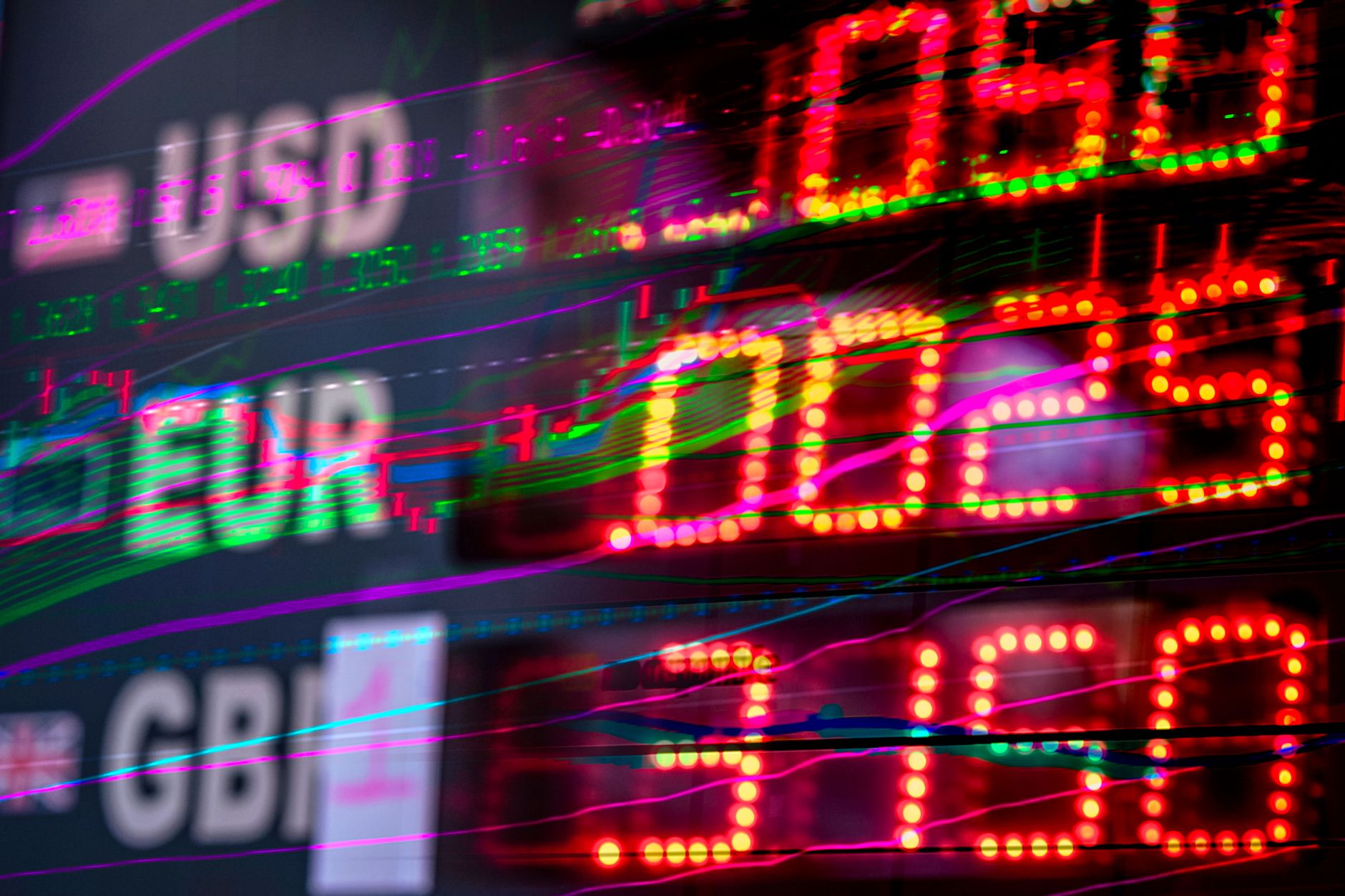 Stock exchange trading floor with large electronic boards showing stock prices.